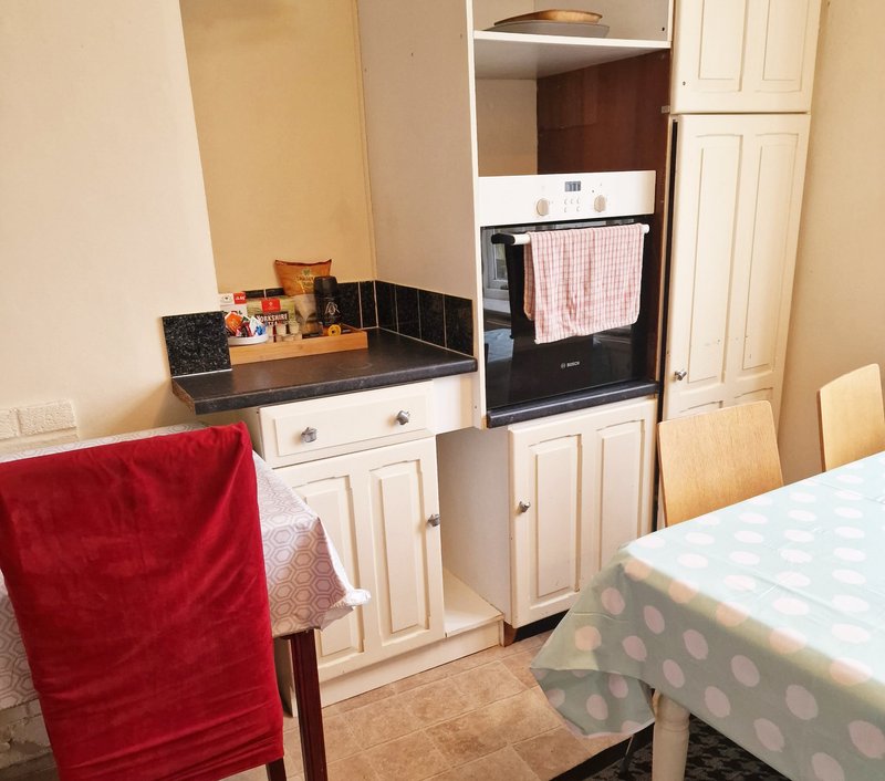 Kitchen area with cream cabinets, black countertop, built-in oven and dining table