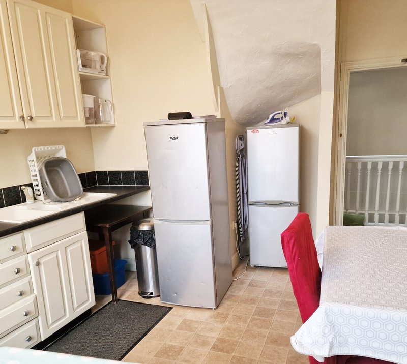 Kitchen area with white cabinetry, two refrigerators, cooker, and tiled flooring