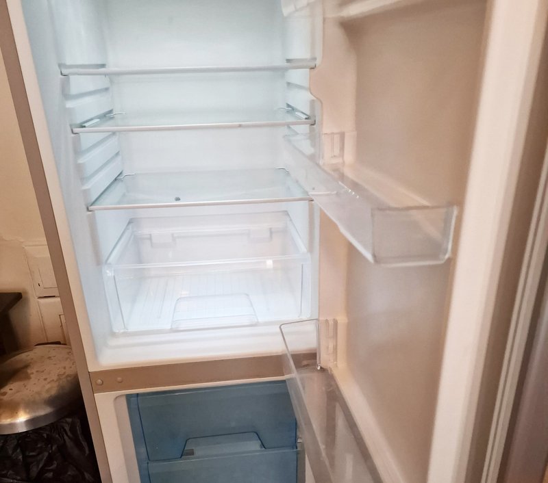 Open refrigerator with empty shelves and freezer compartment below