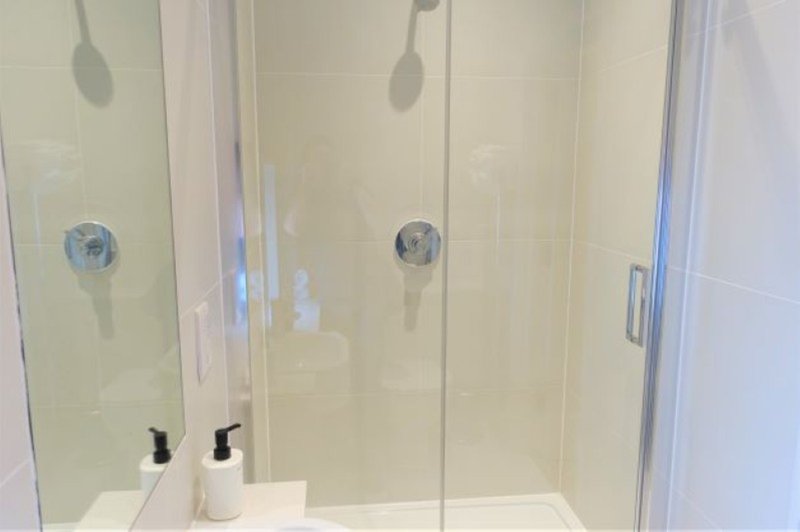 Modern bathroom shower enclosure with glass doors and white tile walls