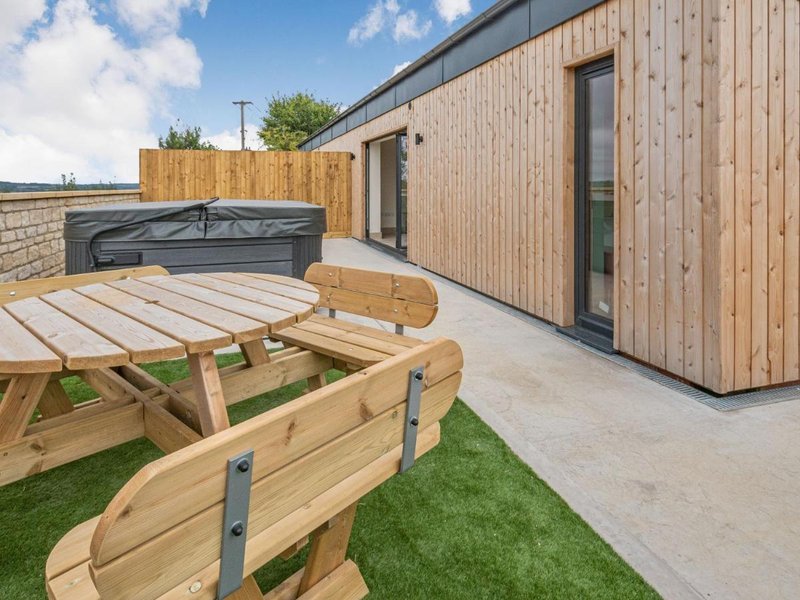 Modern garden with wooden decking, picnic table, hot tub and contemporary wooden building