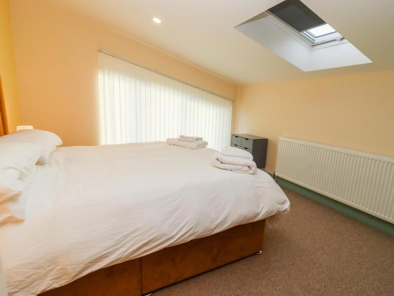 Bright attic bedroom with double bed, skylight window, vertical blinds and radiator