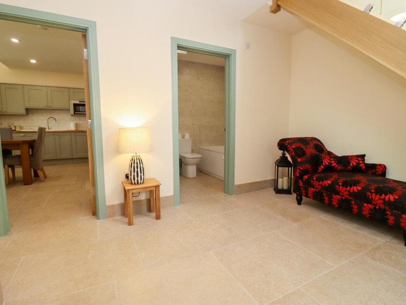 Open-plan living area with kitchen, bathroom access, and red patterned seating