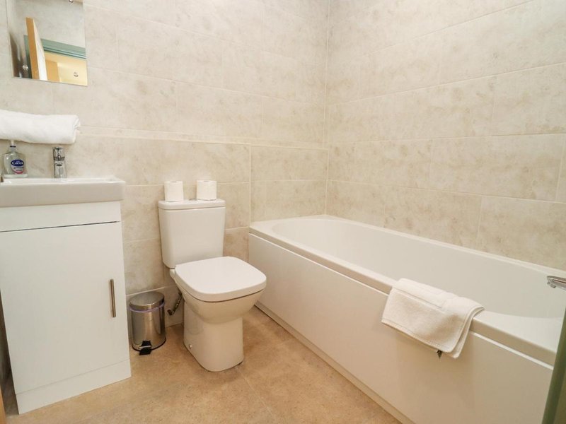 Clean bathroom with bathtub, toilet, sink, and beige tile walls