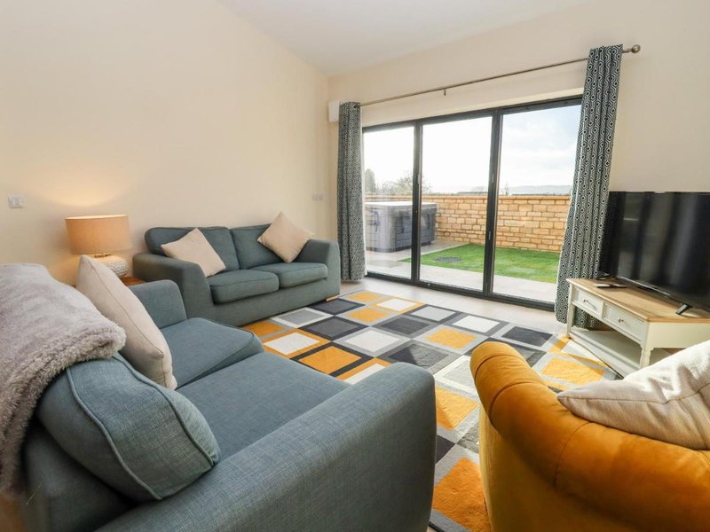 Modern living room with grey sofas, yellow armchair, patterned rug and patio doors