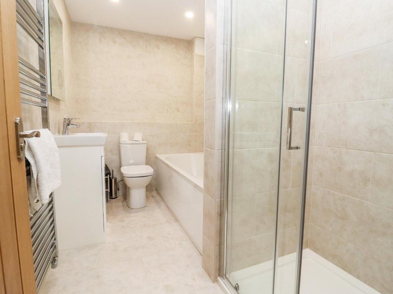 Modern bathroom with walk-in shower, toilet, sink, heated towel rail and beige tiling