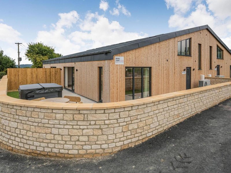 Modern brick and timber-clad house exterior with curved stone wall and driveway