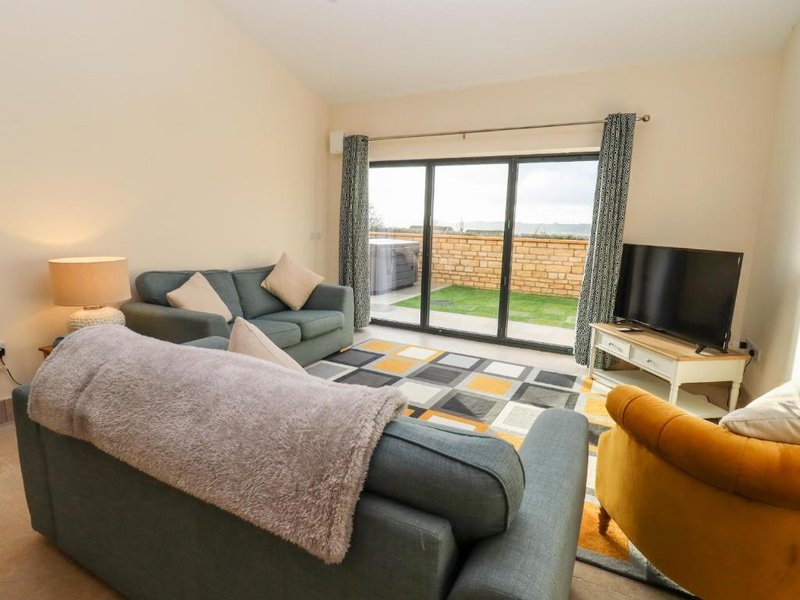 Modern bedroom with double bed, TV, armchair and patio doors overlooking garden