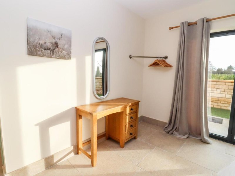 Bright bedroom with wooden desk, mirror, curtains and view to countryside