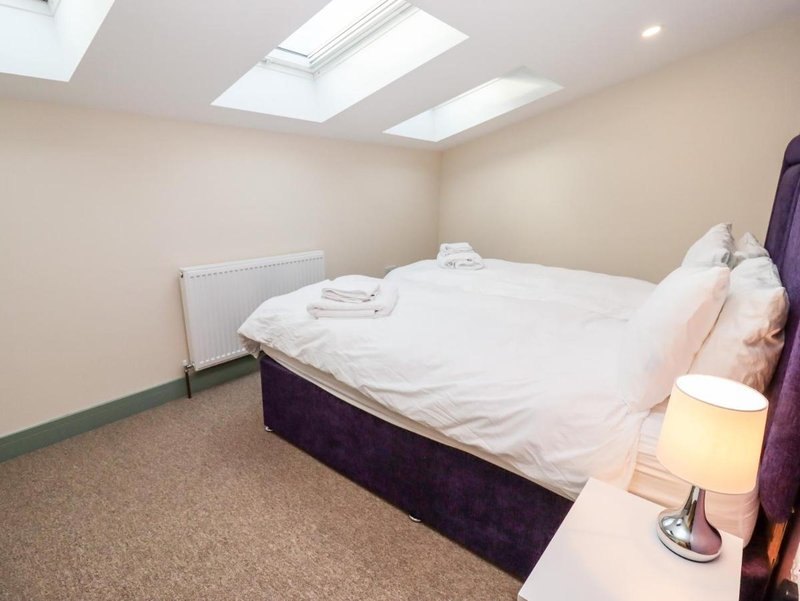 Attic bedroom with double bed, white bedding, skylight windows and bedside lamp