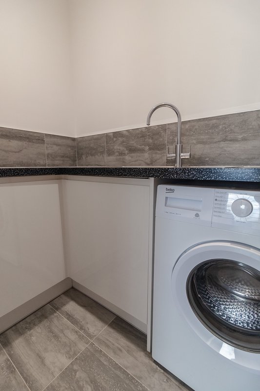 Utility room with washing machine, sink, and tiled walls