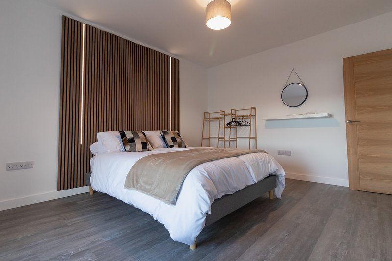 Modern bedroom with double bed, wooden floor, brown curtains and ceiling light