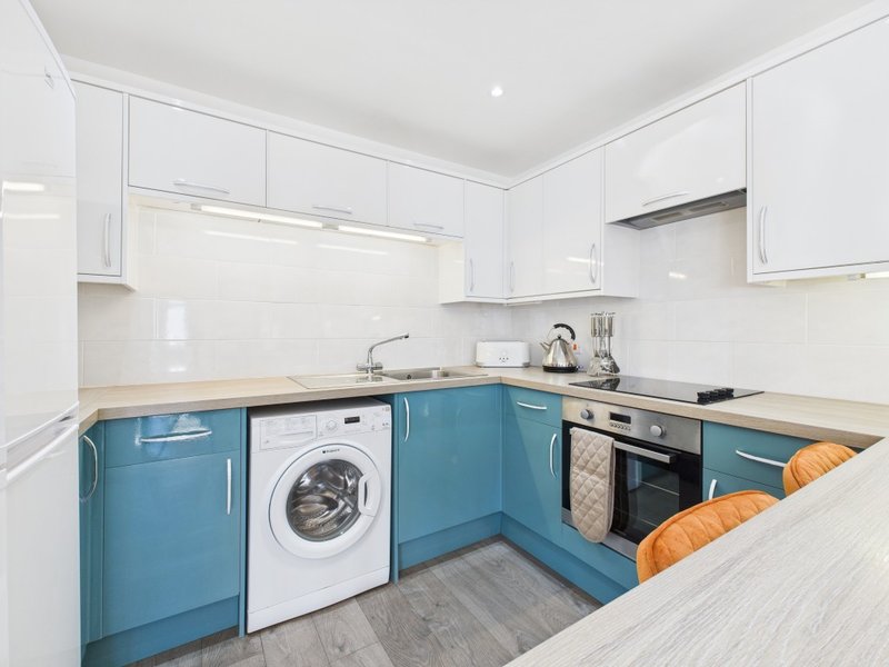 Modern kitchen with blue and white cabinetry, integrated appliances, and wooden countertops