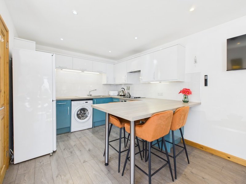 Modern kitchen with white cabinetry, blue base units, island seating and dining area