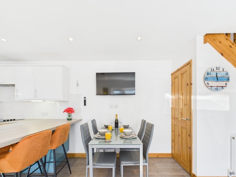 Modern open-plan kitchen and dining area with white cabinetry, dining table, and wooden accents