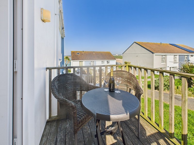 Exterior wooden deck with table, chairs and railing overlooking countryside