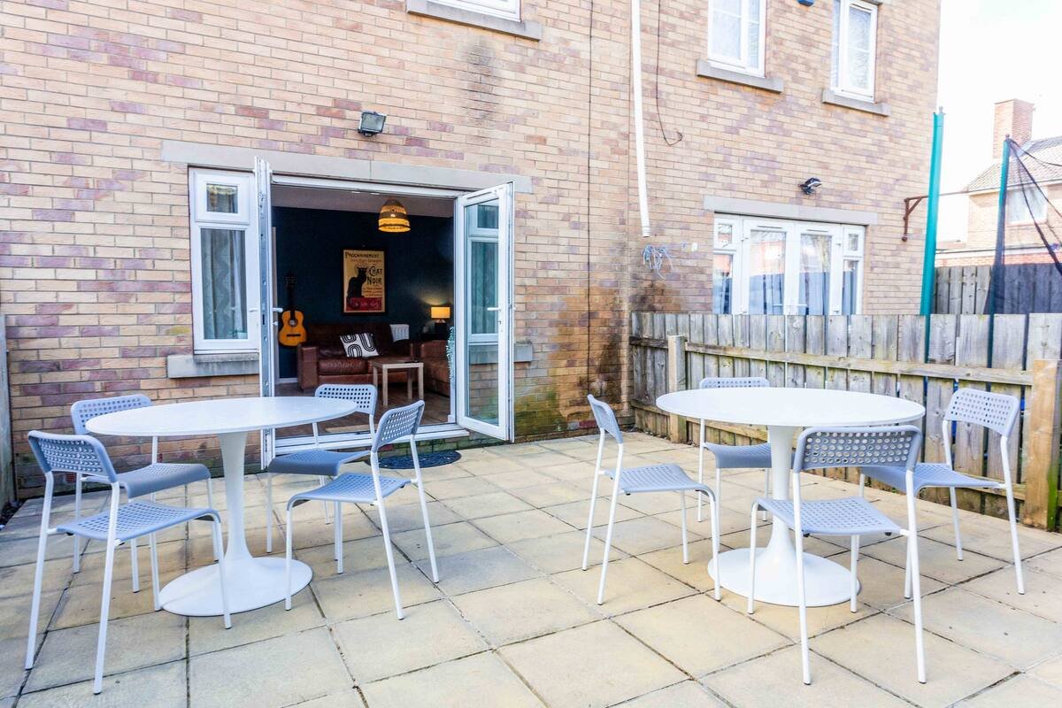 Brick patio with outdoor dining tables, chairs, and open patio doors to interior