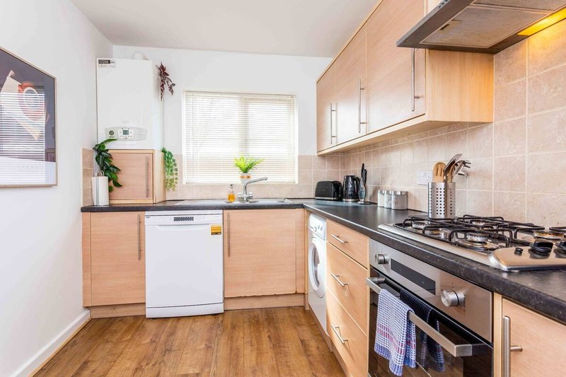 Modern kitchen with light wood cabinets, black countertop, gas range and white appliances