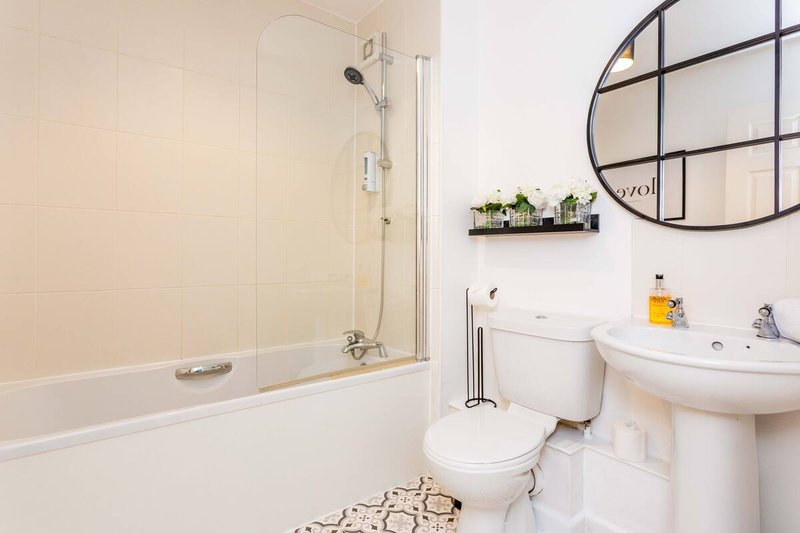 Clean modern bathroom with bathtub, shower enclosure, pedestal sink and round mirror