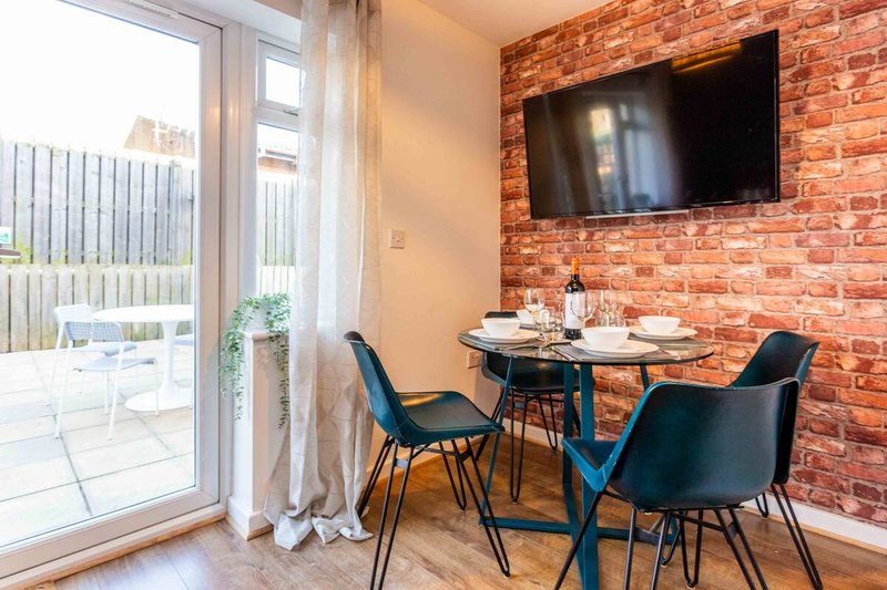 Modern dining area with brick accent wall, mounted TV, and glass doors to patio