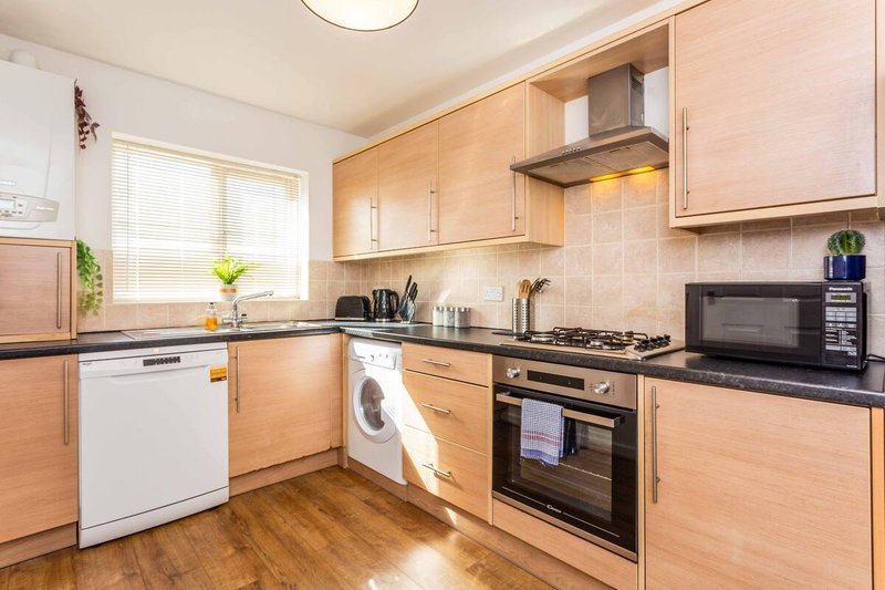 Modern kitchen with wooden cabinets, black countertops, gas cooker and stainless steel appliances