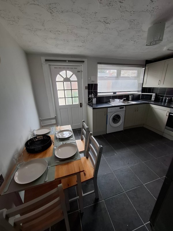 Kitchen-diner with wooden table, place settings, washing machine and fitted units