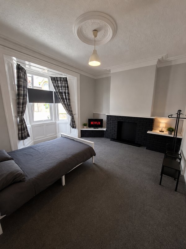Spacious bedroom with double bed, fireplace, desk area and patio doors with curtains