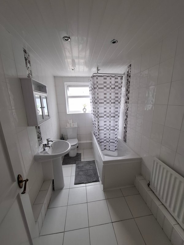 Bright bathroom with white tiles, sink, shower enclosure and radiator
