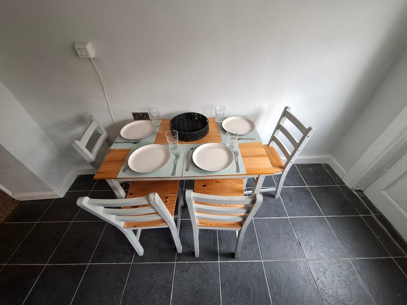 Dining table set for four with white plates, black cookware, and wooden chairs