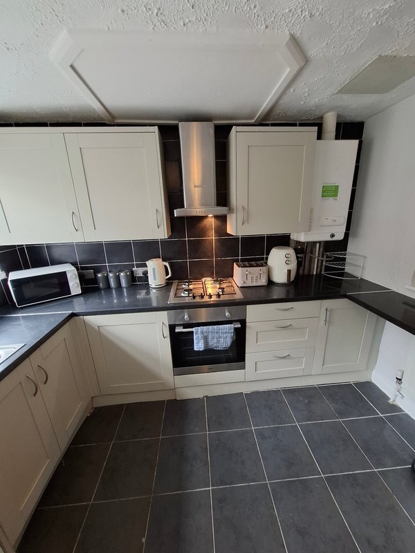 Modern kitchen with cream cabinets, black countertop, gas hob and built-in oven