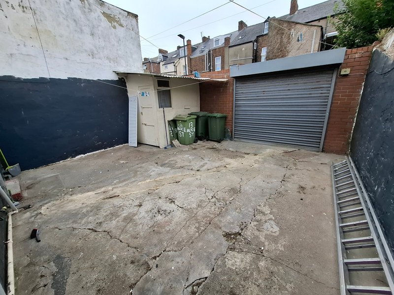 Concrete yard with garage door, bins, and surrounding brick buildings