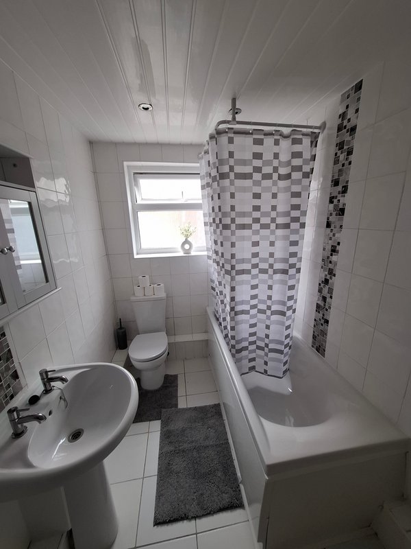 Small bathroom with toilet, sink, shower enclosure and checkered tile walls