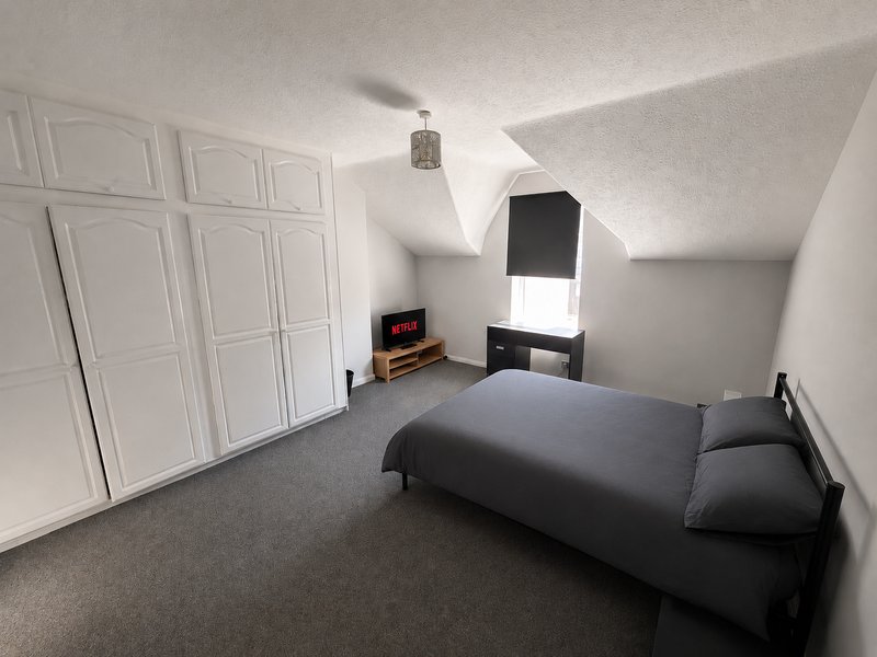 Attic bedroom with double bed, built-in wardrobe, small desk and skylight window
