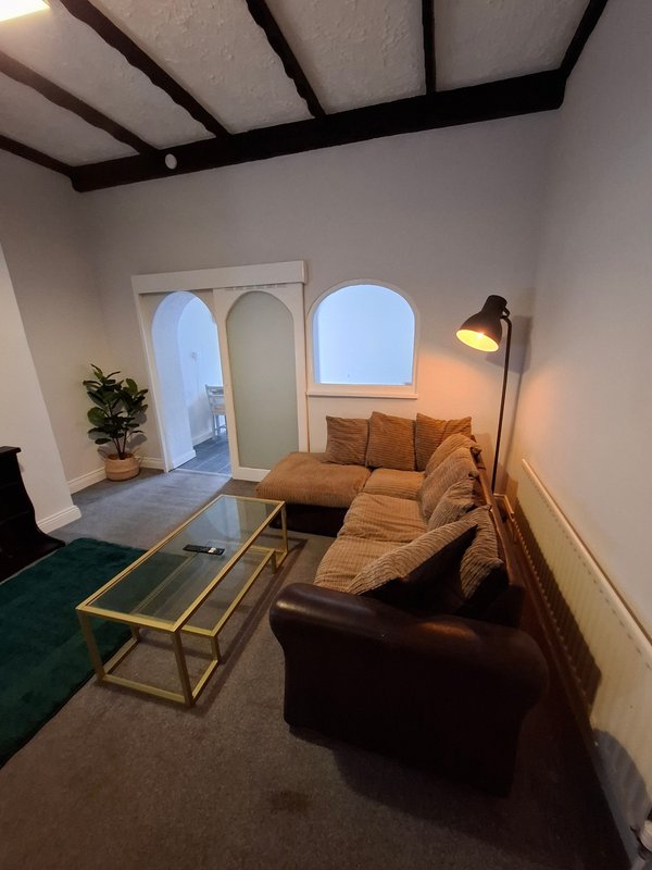 Modern living room with brown sofa, glass coffee table, arched windows and floor lamp