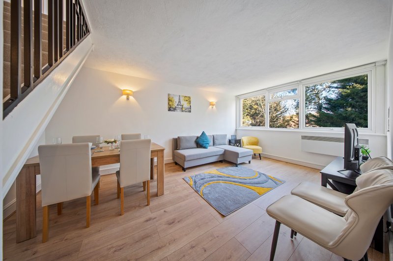 Open-plan living and dining room with wooden floor, sofa, dining table and stairs