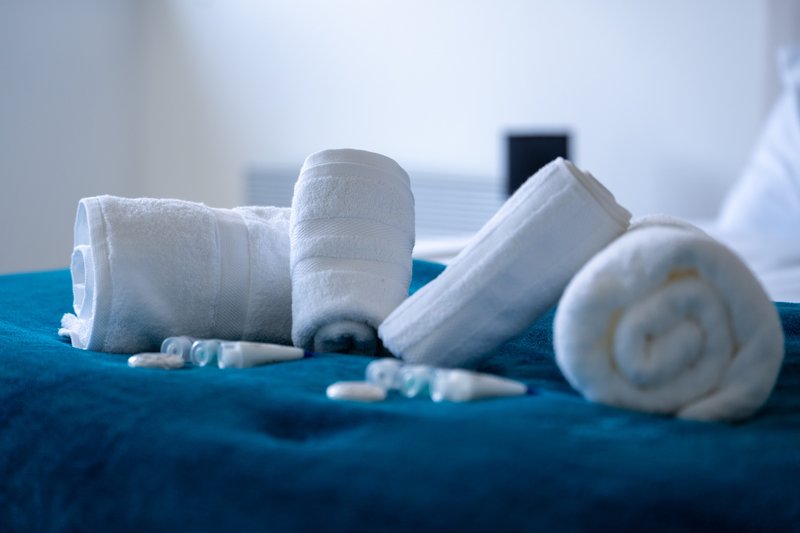 White rolled towels and toiletries arranged on blue fabric surface