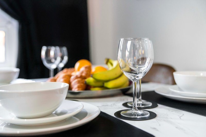 Formal dining table set with white plates, wine glasses, and fresh fruit bowl