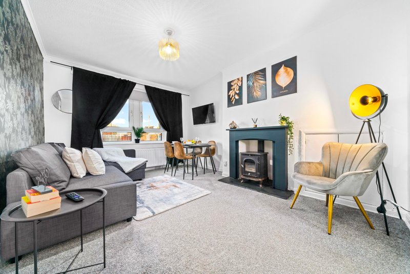 Modern living room with grey sofa, fireplace, dining area, and yellow accent chair