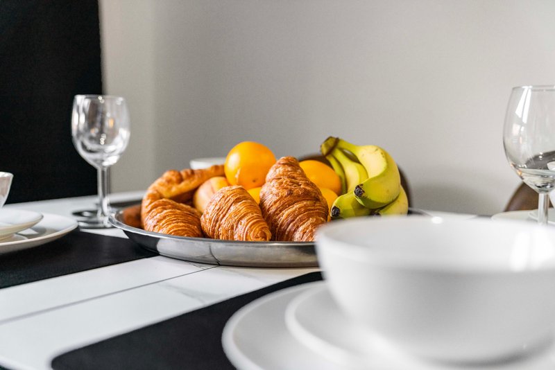 Breakfast table with croissants, fruit, wine glasses and place settings