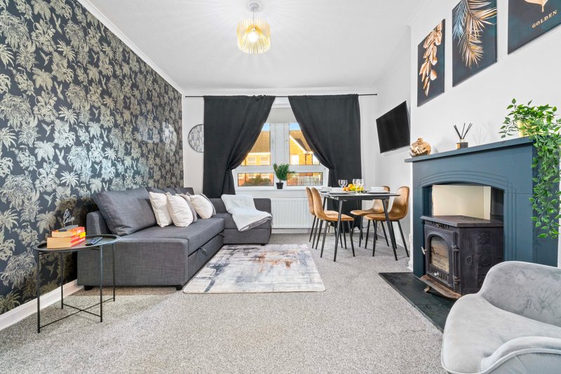 Open-plan living room with grey sofa, dining table, blue fireplace and patterned feature wall