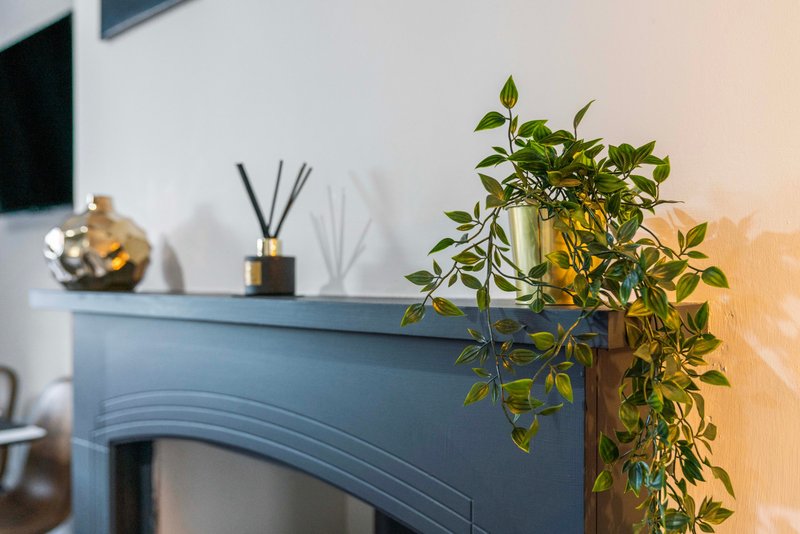 Blue fireplace mantel with potted plant, reed diffuser and decorative items