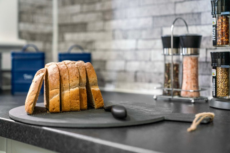 Modern kitchen with black countertop, sliced bread, storage containers and organized shelving