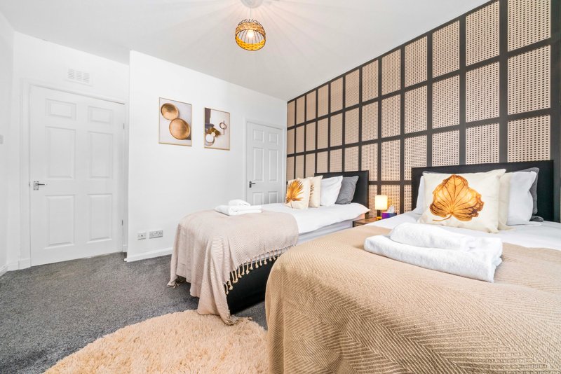 Modern bedroom with three beds, geometric wall feature, pendant light and neutral furnishings