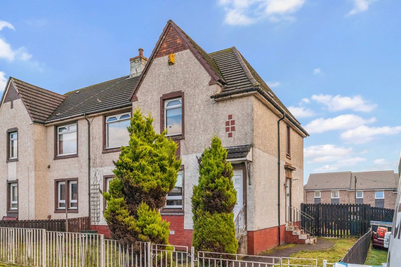 Stone semi-detached house with red door, gardens and white fence