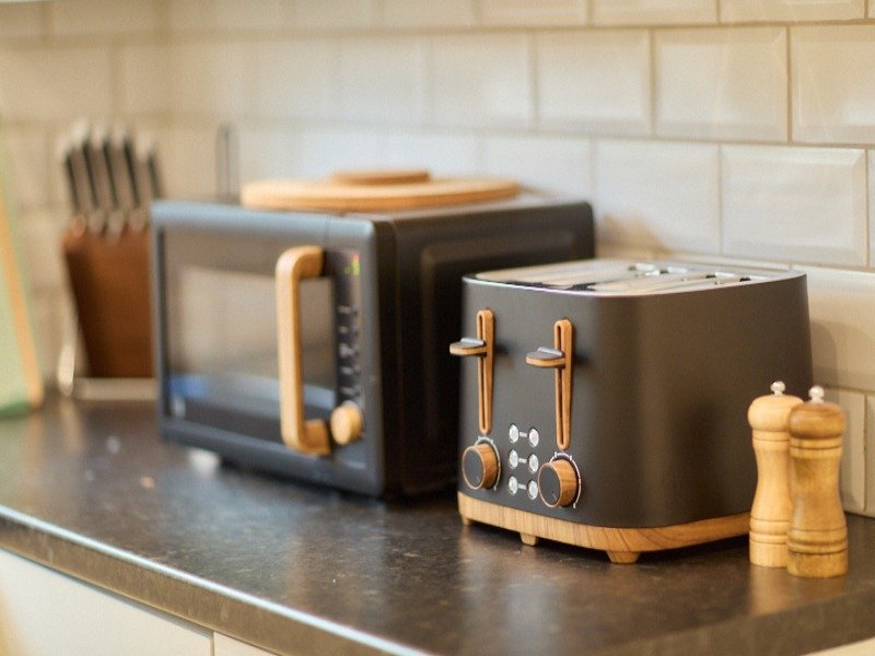 Modern kitchen counter with black toaster, microwave, and wooden kitchen accessories
