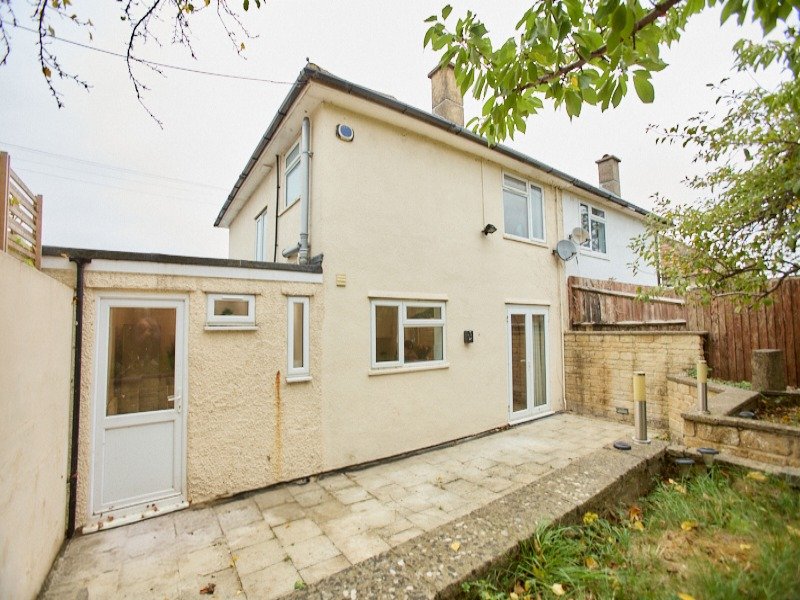 Cream-coloured two-storey house exterior with patio, garden and wooden fence
