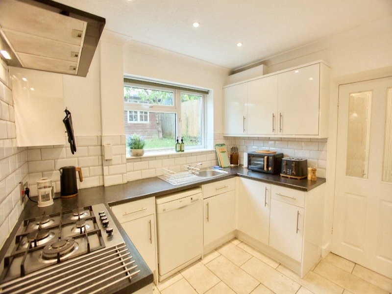 Modern kitchen with cream cabinets, gas hob, sink and window overlooking garden