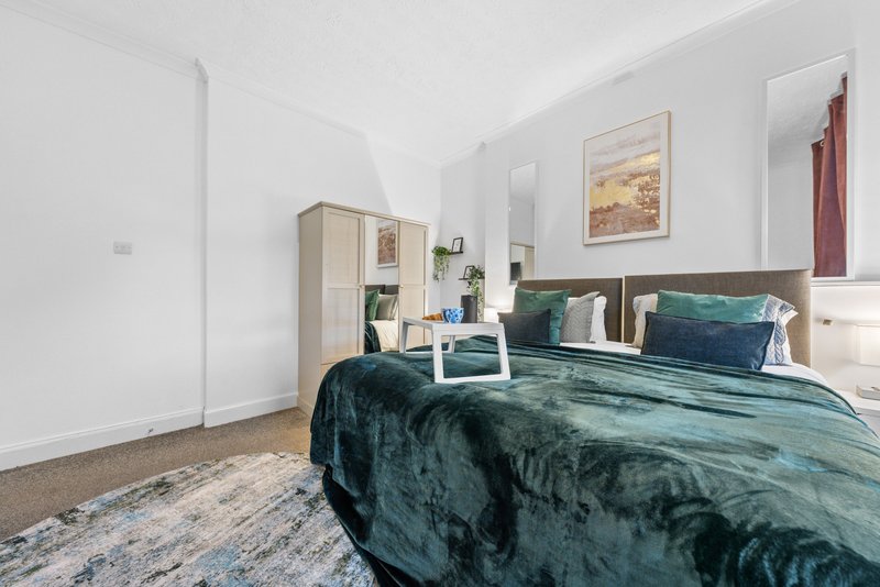 Modern bedroom with double bed, teal bedding, wooden headboard, wardrobe and wall art