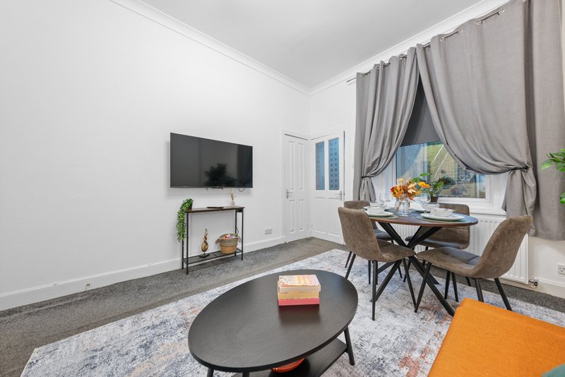 Modern living room with TV, dining table, black oval coffee table and grey curtains