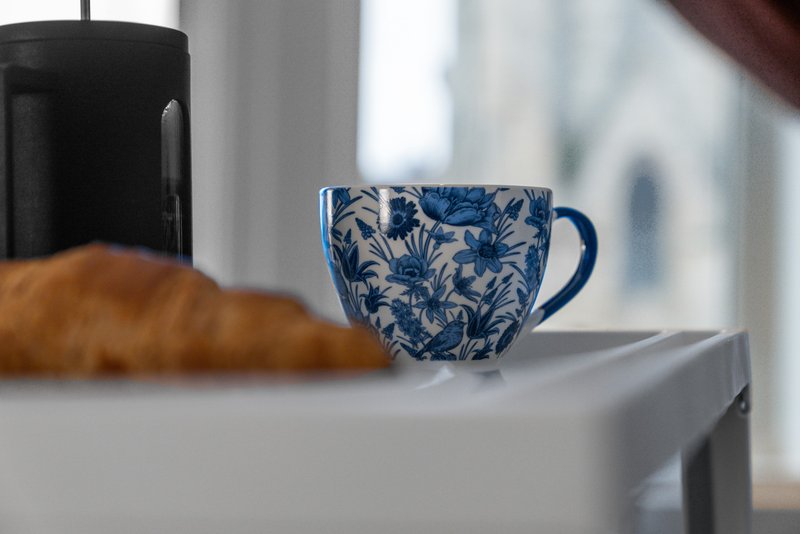 Kitchen counter with decorative blue and white patterned mug, black kettle, and bread